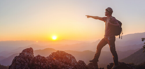 Wall Mural - Hiker standing on top mountain sunset background. Hiker men's hiking living healthy active lifestyle.