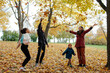 © Sergey Narevskih/Stocksy - Diverse family tossing leaves in air