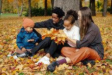 Diverse Family Resting In Autumn Park