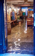 © Adam Sébire/Stocksy - High tide floods shop and restaurant in Venice