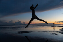 Girl Jumping On The Beach At Sunset 