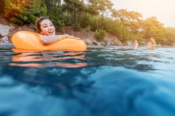 Wall Mural - A carefree and happy young girl swims in an inflatable circle on the seashore. Resort and recreation concept. Infantilism and childishness