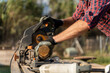 © Alba Vitta/Stocksy - Man sawing a piece of wood outdoors