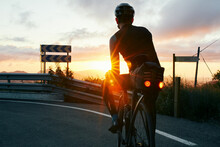 Golden Hour Cyclist Watching Sunrise On Mountain Road