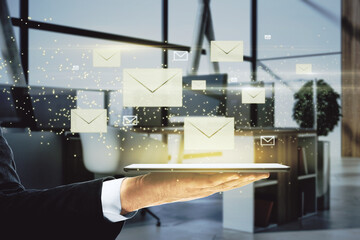 Poster - Close up of businessman hand holding tablet with creative glowing letters interface on blurry office interior background. E-mail networking and correspondence concept.