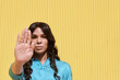 © Westend61 - Non-binary woman showing stop gesture in front of yellow wall