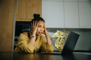 Woman with head in hands looking at Trojan virus icon on laptop