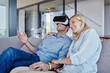 © Westend61 - Smiling woman sitting by man wearing virtual reality simulator in living room