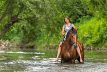 Young woman riding horse in river at forest