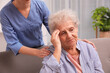 © New Africa - Nurse taking care of senior woman with headache indoors