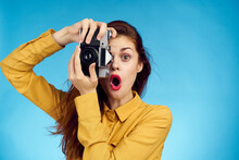 Pretty Woman Photographer With Camera In Yellow Shirt On Blue Background