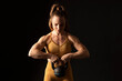 © Westend61 - Athlete woman exercising with kettlebell against black background