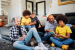 © Westend61 - Multiethnic family using smart phones while sitting together in living room at home