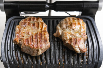 Hot steak on the electric grill at home in the kitchen