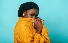 Woman Covering Face With Overcoat In Front Of Blue Background
