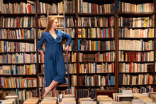 Smiling Woman Looking Away While Standing On Ladder In Library