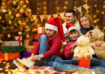 Wall Mural - Happy family posing in new year or christmas decoration. Children and parents. Holiday lights and gifts, Christmas tree decorated with toys.