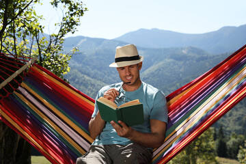 Sticker - Handsome man reading book in hammock outdoors on sunny day