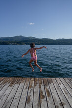 Young Girl Leaps Into Lake From Dock