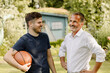 © Westend61 - Cheerful son with basketball looking at father while standing in back yard