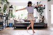 © Westend61 - Carefree woman with arms outstretched dancing at home