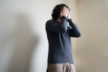 Man Covering Face With Hands While Standing At Home