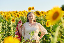 Senior Woman Standing With Hand On Hip In Sunflower Field