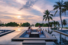 Couple Watching The Sunset In An Infinity Pool On A Luxury Vacation In, Man And Woman Watching The Sunset On The Edge Of A Pool