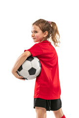 Wall Mural - Cropped side view portrait of girl, child, in red football player uniform posing with ball isolated over white background