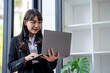© crizzystudio - Portrait of businesswoman standing Using Laptop in office working on laptop typing business e-mail, check media news, solve current work-related issues distantly, communication online concept