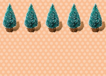 Studio Shot Of Row Of Coniferous Trees Standing Against Beige Polka Dot Background