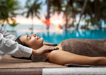 Poster - wellness, beauty and relaxation concept - beautiful young woman having hot stone massage at spa over tropical beach background in french polynesia