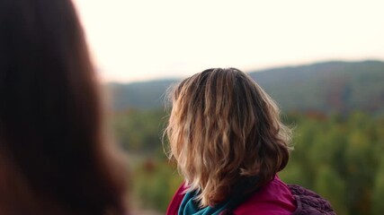 Wall Mural - Two girls admire the mountain landscape at sunset, a woman climbed to the top and looks at a beautiful valley