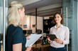 © Westend61 - Young businesswoman discussing with female colleague while standing at doorway in office