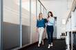 © Westend61 - Female entrepreneurs discussing plan over digital tablet while walking in office corridor