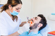 © Westend61 - Female dentist wearing protective face mask examining male patient's teeth at medical clinic