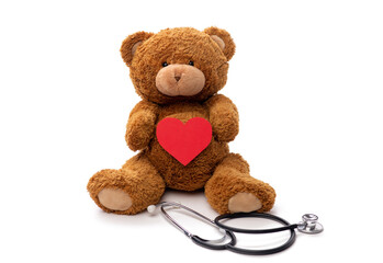 Wall Mural - medicine, healthcare and childhood concept - teddy bear toy with stethoscope holding red heart on white background