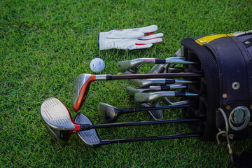 Wall Mural - Closeup old golf bags on green. Set of golf clubs over green field background