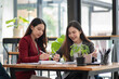 © Songsak C - Two casual Asian businesswomen discussing work in the office