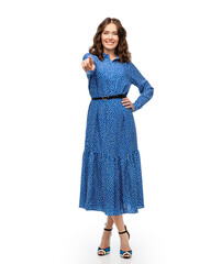 Wall Mural - fashion, style and people concept - happy smiling beautiful young woman posing in blue dress pointing to camera over white background