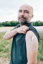 Vaccinated Man Showing Bandage By Tattoo On Arm
