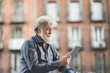 © Westend61 - Mature man with white hair using digital tablet in city