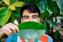 Young Man Covering Mouth With Green Leaf