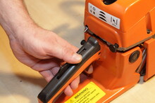 A Man's Hand Holding The Handle And Pulls The Chainsaw Throttle Trigger Close-up - Power Tools Equipment Service