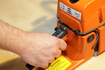 Poster - A man's hand holding the chainsaw handle with the throttle trigger of the closeup - forester tools equipment service