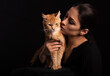 © Anastasia.photoyoga - Beautiful make-up woman hugging and kissing with love her red maine coon kitten. Closeup portrait. Art on black background