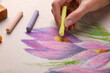 Woman drawing beautiful crocus flowers with soft pastel, closeup