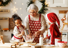 Happy Multiracial Kids Help Grandmother To Cook Christmas Cookies In Kitchen During Winter Holidays
