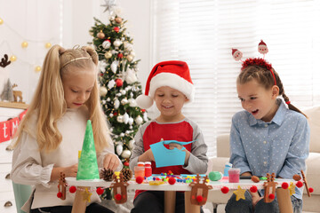 Sticker - Cute little children making Christmas crafts at table in decorated room