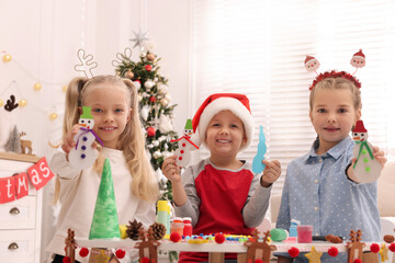 Poster - Cute little children with beautiful Christmas crafts at table decorated in room